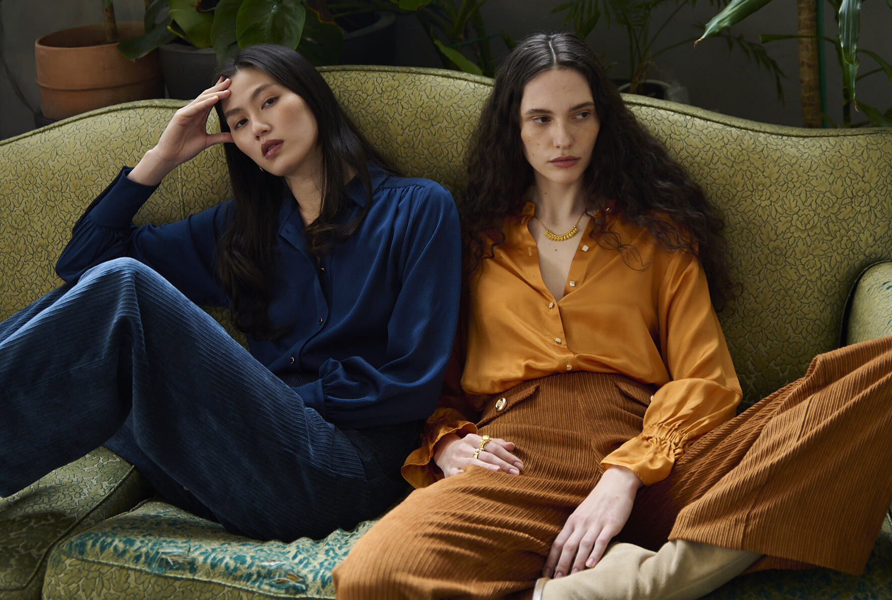 two girls sitting wearing a blue blouse with navy corduroy trousers